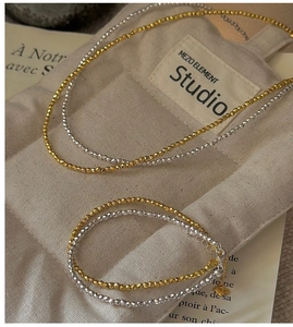 Macro shot of gold and silver faceted S925 beads bracelet on a canvas bag background