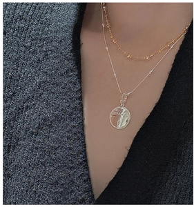 Détail d'un collier superposé en argent S925 avec pendentif étoile sur tricot noir