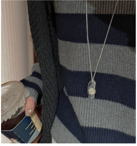 Close-up of S925 sterling silver geometric pendant necklace on striped sweater