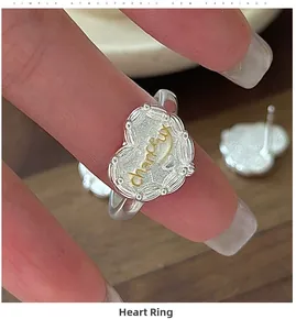 Dettaglio dell'anello a cuore in argento S925 con incisione chanceux dorata sulla mano