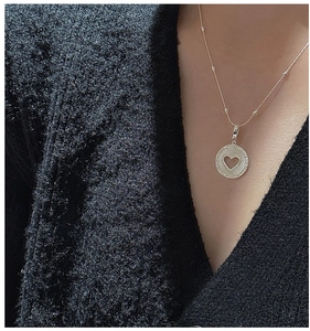 Détail d'un collier en argent sterling S925 avec pendentif cœur sur un pull sombre