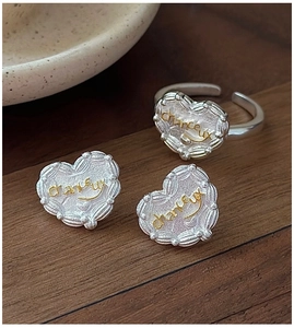 Detail of S925 silver heart jewelry set with golden lucky engraving on matte finish