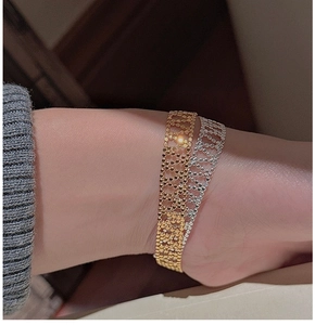 Nahaufnahme der geflochtenen Metallarmbänder in Gold und Silber an einem Handgelenk
