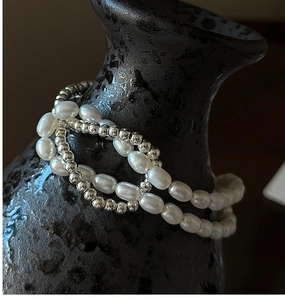Gros plan de perles en argent S925 et perles d'eau douce sur un bracelet à nœuds