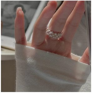 Detail of a minimalist S925 sterling silver beaded ring with a wide mesh design on finger
