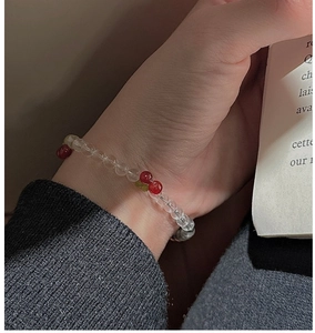 Close-up of a handmade beaded cherry bracelet with red and green charms on a model's wrist