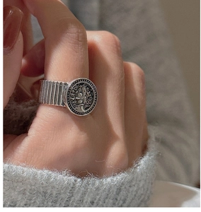 Close-up of vintage S925 silver coin ring with textured band worn on model hand