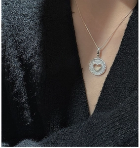 Gros plan du collier S925 en argent avec pendentif cœur sur tricot noir élégant