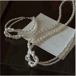 Gros plan du collier noué en perles d'argent S925 et perles d'eau douce blanches sur fond