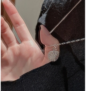 Detail of S925 sterling silver apple pendant necklace with radiant texture on dark knitwear