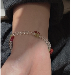 Detailed close-up of a beaded cherry bracelet with red and green beads on a wrist