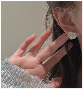 Macro shot of S925 silver heart earring with cream resin and golden baby lettering