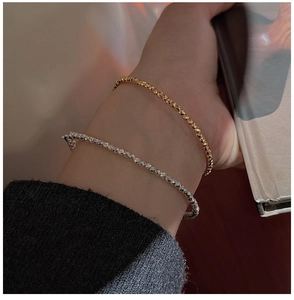 Close-up of stacked gold and silver minimalist faceted bead bracelets on a model wrist