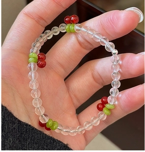 Macro detail of cherry beaded bracelet with clear crystals and red fruit charms