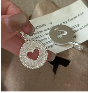 Gros plan du pendentif cœur en argent S925 avec motif rayon de soleil et poinçons