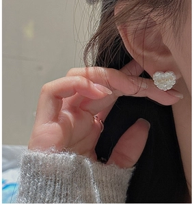 Close-up of S925 sterling silver heart-shaped stud earring with wavy lace edges on model
