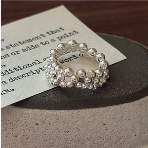 Macro shot of S925 sterling silver woven beaded ring on a minimalist ceramic plate