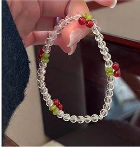 Close-up of beaded cherry bracelet featuring clear beads and red cherry charms on wrist