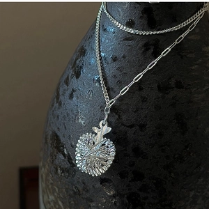 Detail of silver double-layer paperclip curb chain with circular relief pendant necklace
