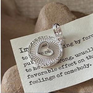 Détail macro du pendentif coeur en argent S925 avec texture soleil et bordure tressée