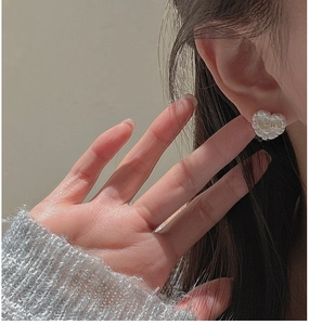 Close-up of heart-shaped resin earrings featuring inlaid LOVE letters on model