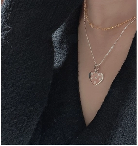 Detail of layered S925 sterling silver necklaces with heart pendant and gold bead chain