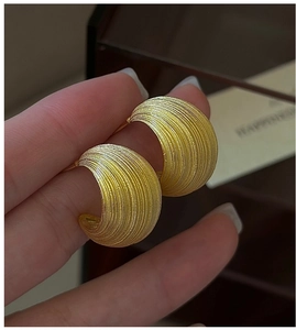 Macro shot of gold S925 silver C-shape earrings with a brushed matte texture finish
