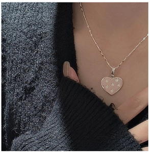 Detail of S925 silver heart pendant with pink enamel and star motifs on a beaded chain