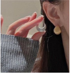 Macro detail of fan-shaped S925 sterling silver earrings with brushed metal texture