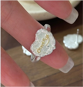 Dettaglio macro di un anello in argento a cuore con incisione 'chanceux' e finitura martellata