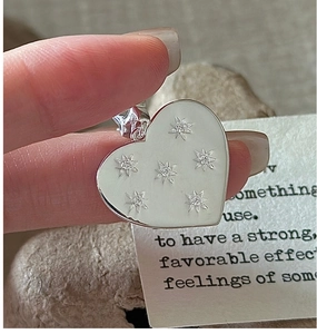 Detailed view of S925 silver heart pendant with white enamel and silver star patterns