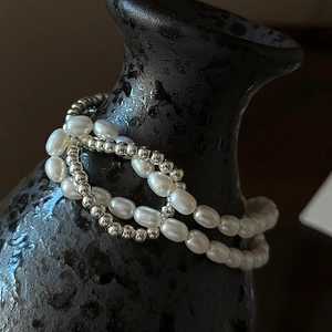 Bracelet double couche en argent S925 et perles baroques sur un vase en céramique