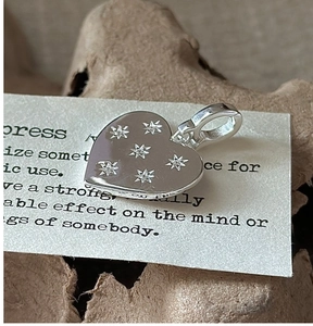 Detailed macro shot of S925 sterling silver heart pendant with star pattern engravings