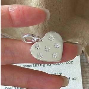 Macro shot of 925 sterling silver heart charm with inlaid star zircons and polished finish