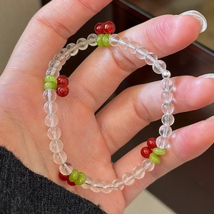 Retro cherry beaded bracelet with red fruit and green leaves on a hand-held wrist