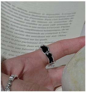 Detailed view of silver wave ring with black enamel and tiny cubic zirconia stones