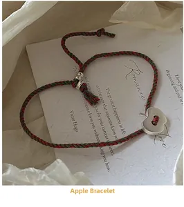 Détail du bracelet en corde tissée rouge et verte avec pendentif pomme en argent mat