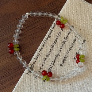 Handmade cherry charm beaded bracelet with clear crystals and red cherry pendants on wood