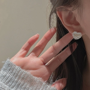 Elegant S925 silver heart earrings with pearl finish and gold letter on a female model