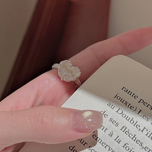 Anello a cuore in argento S925 con incisione chanceux indossato sulla mano con libro