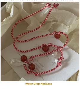 Close-up of hand-woven red cord necklace with agate beads and silver water drop pendant