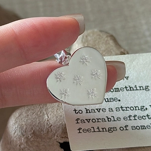 S925 sterling silver heart pendant with floral stones and star charm in hand-held macro shot