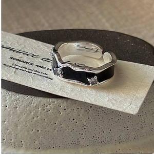Macro shot of silver ring with black enamel details and sparkling white zircon stones