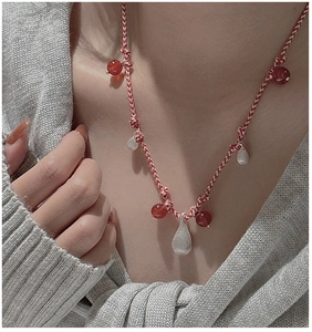Detail of red and white woven S925 silver necklace with drop pendants on a model