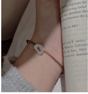 Gros plan d'un bracelet tissé tricolore avec un pendentif pomme en argent porté au poignet