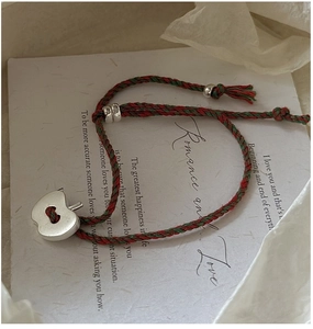 Gros plan du bracelet tressé rouge et vert avec un pendentif pomme en argent mat