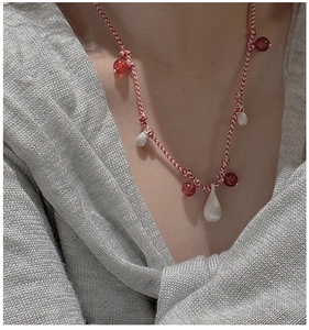 Detail of red and white braided silk cord necklace with white jade drop pendants