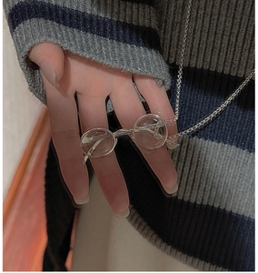 Gros plan détaillé d'un pendentif lunettes argentées rétro sur une fine chaîne maille