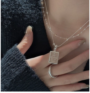 Close-up of S925 silver layered necklace with engraved square pendant and wide band ring