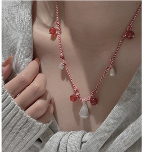 Detailed macro of red woven rope necklace with silver droplets and red agate beads
